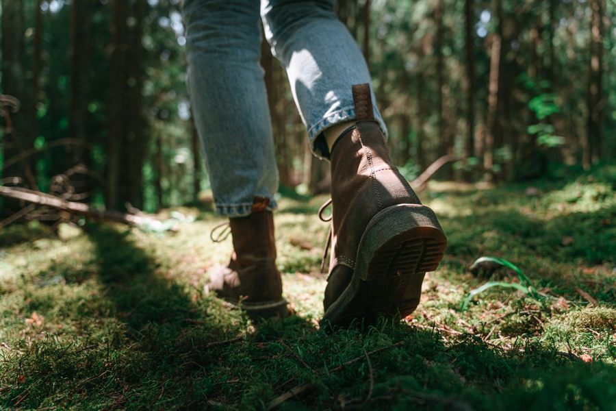 Hiker&rsquo;s leather boots walking on a mossy forest trail