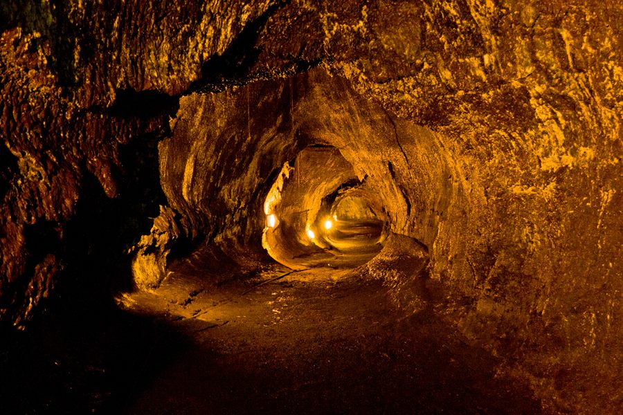 Lit interior of a lava tube cave with rough rock walls