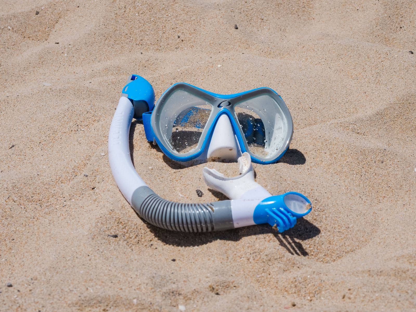 Blue snorkel mask and snorkel lying on sand